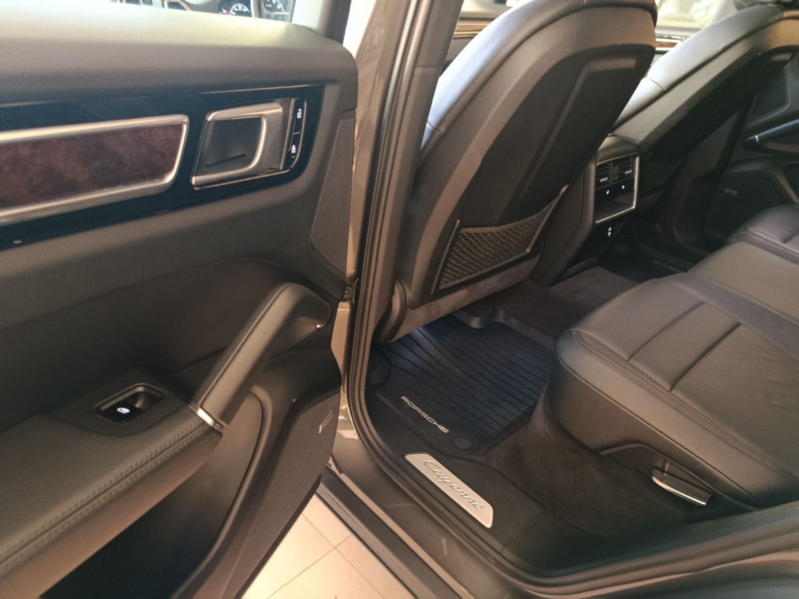 Interior del coche con la puerta trasera del pasajero abierta, mostrando los asientos de cuero negro 