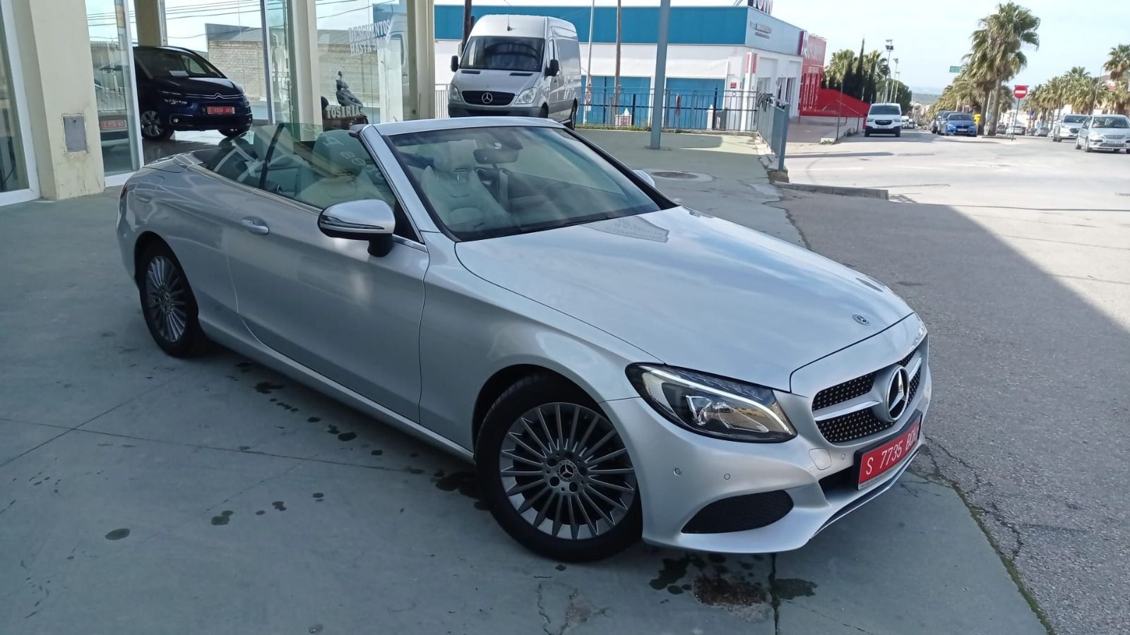 Mercedes-Benz descapotable plateado estacionado al aire libre en un aparcamiento, vista frontal izquierda.