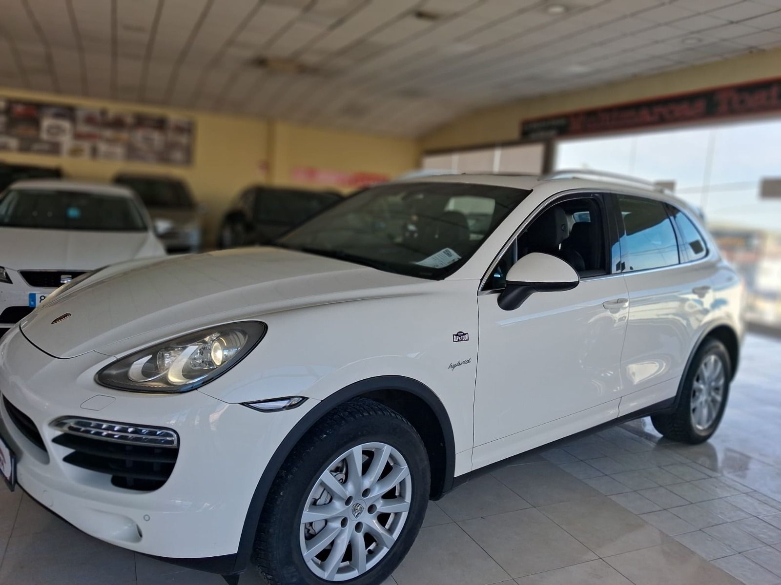 SUV blanco estacionado en el interior de una sala de exposición, vista frontal izquierda en ángulo.
