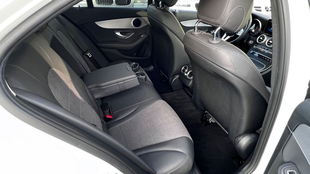 Asiento trasero de coche con tapicería oscura y respaldos visibles a través de una puerta abierta.