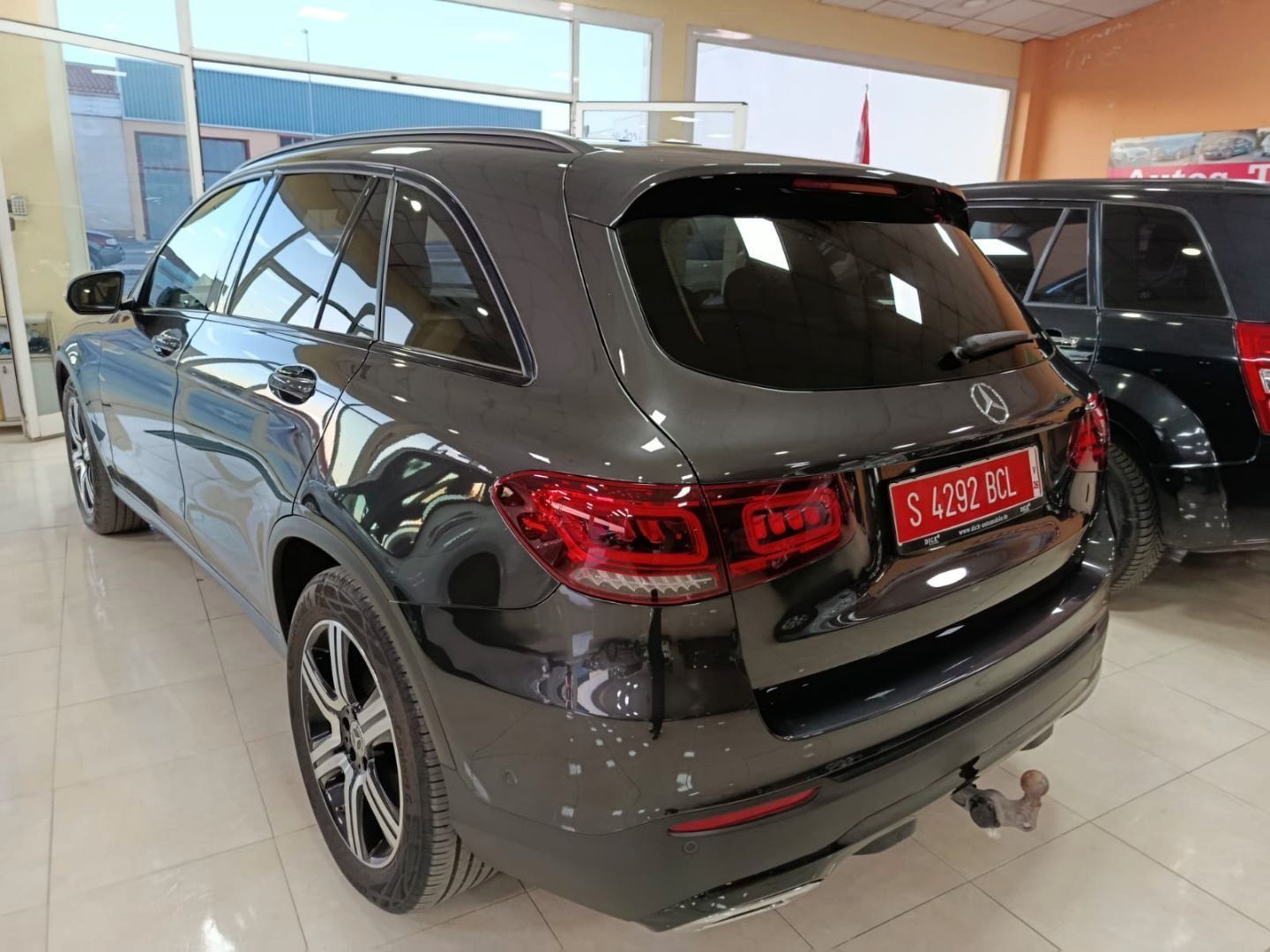 SUV gris oscuro visto desde atrás dentro de una luminosa sala de exposición de automóviles.