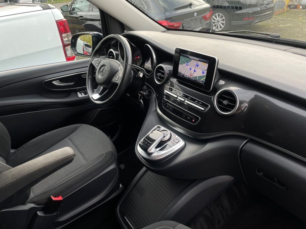 Interior de un automóvil con asientos negros, pantalla en el tablero, volante y consola central en un vehículo estacionado.