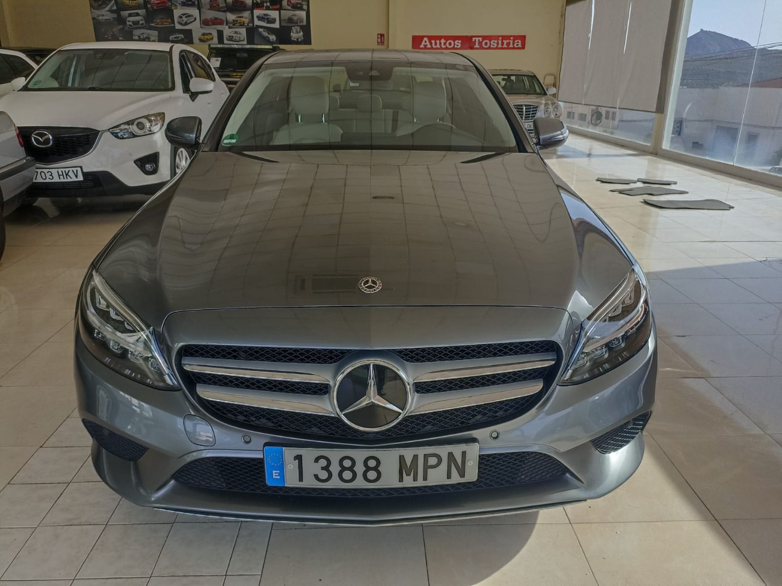 Mercedes sedán gris estacionado en el interior, vista frontal con matrícula 1388 MPN.