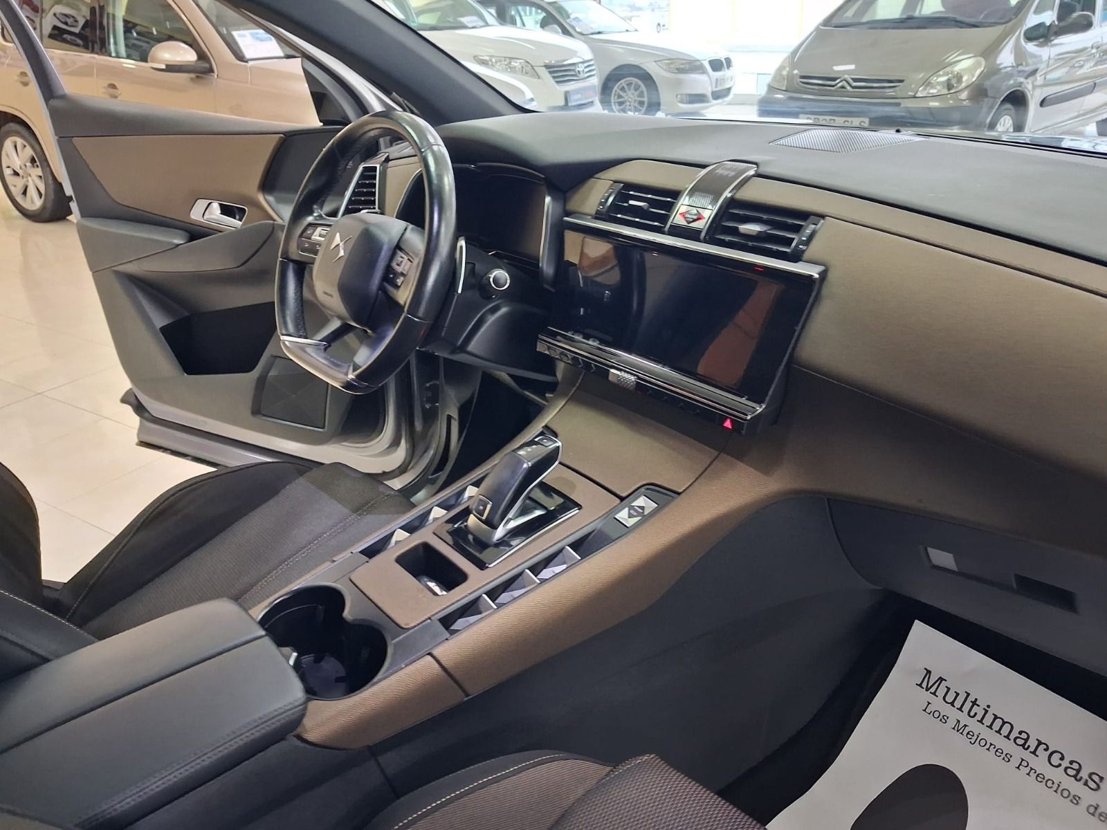 Interior de un automóvil con asientos de cuero negro, tablero con pantalla táctil y consola central 