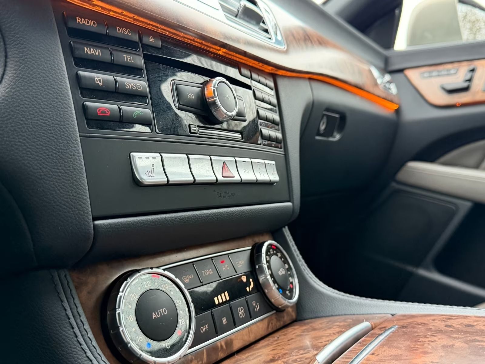 Tablero de instrumentos de lujo con detalles en madera, controles de climatización y selector de marchas