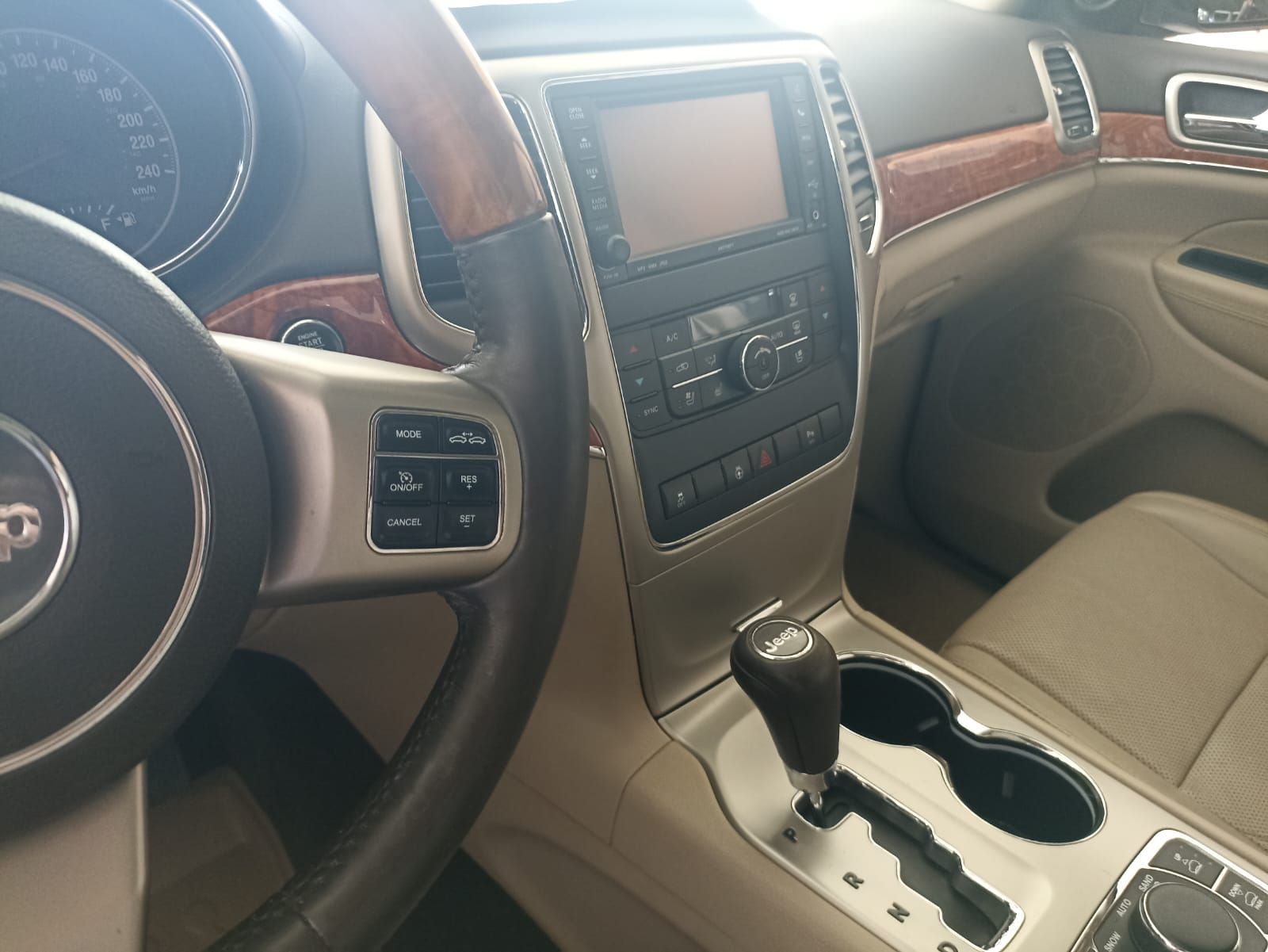 Interior del coche con asientos de cuero color canela, detalles en madera, consola central y volante.