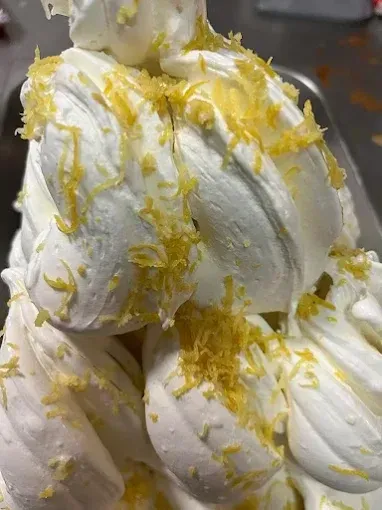 Merengue blanco o postre batido cubierto con ralladura amarilla, apilado en primer plano.