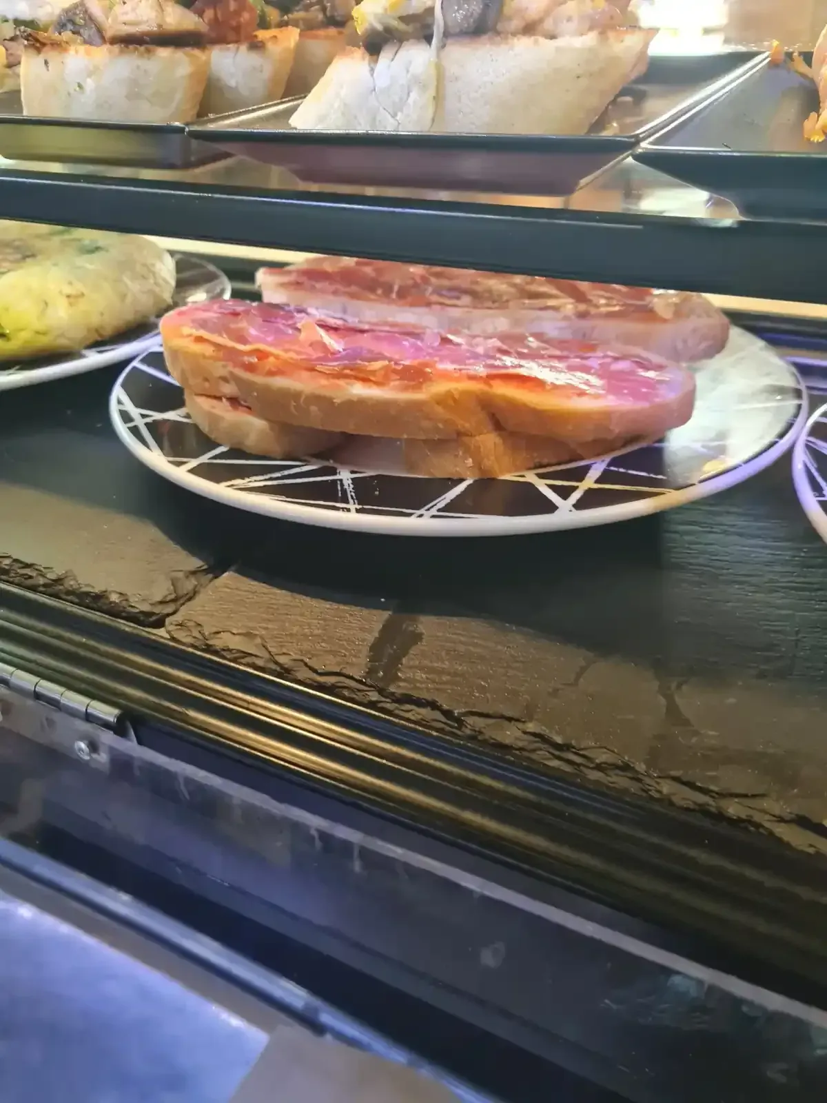 Sándwiches con carne en un plato dentro de una vitrina.