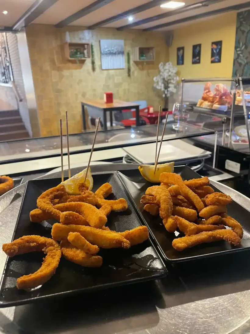 Dos platos de comida frita con gajos de limón en un restaurante.