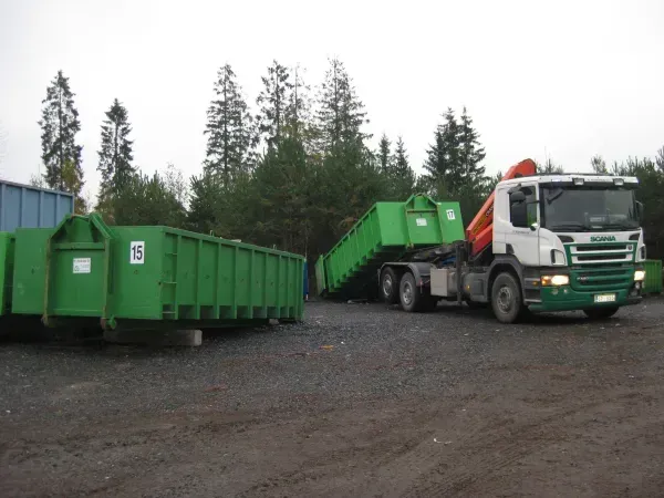 Vihreää roskalavaa lastataan kuorma-autoon ulkona sijaitsevalla jätelaitoksella.