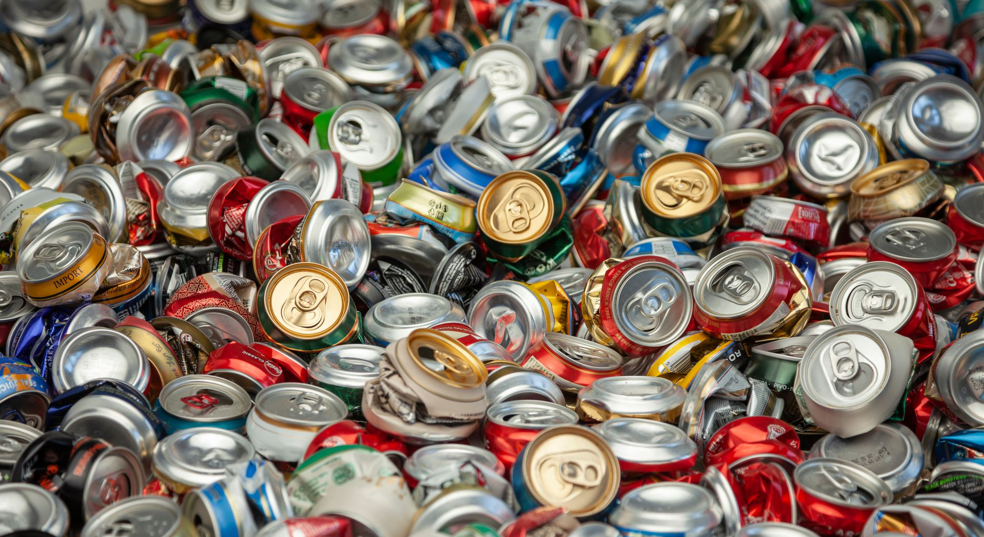 Tas de canettes de boissons en aluminium écrasées et ouvertes.