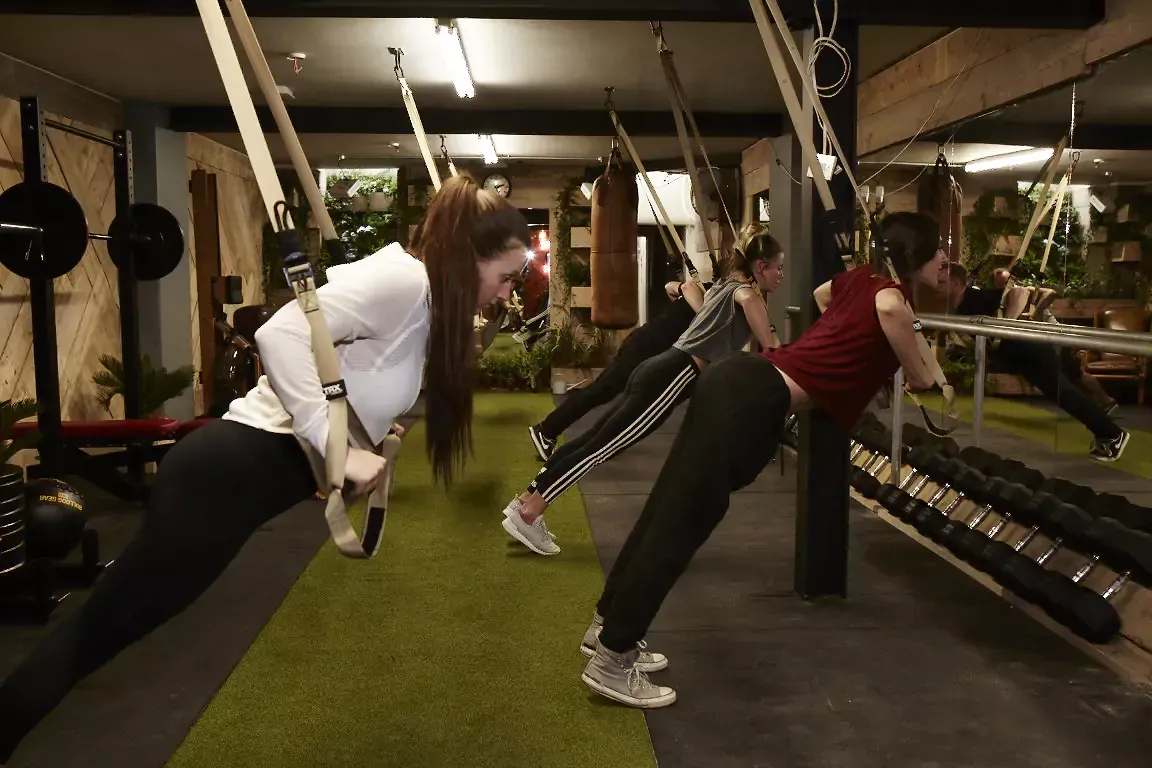 A group of women are doing trx exercises in a gym.