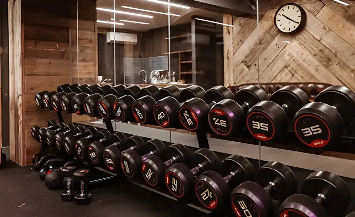 A gym with a lot of dumbbells and a clock on the wall.