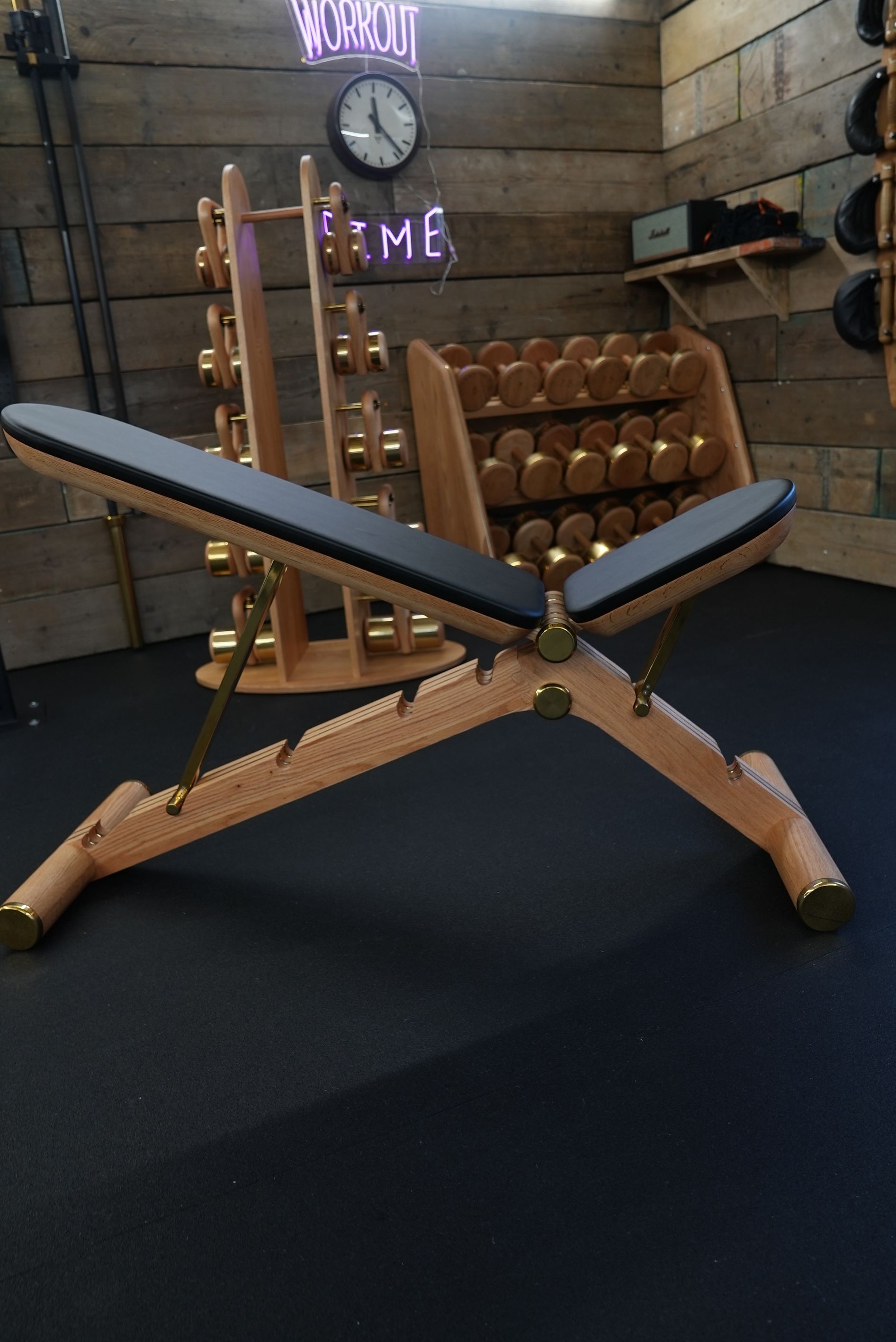 Terra Hale Gym Design: A wooden bench is sitting in a gym next to a rack of dumbbells.