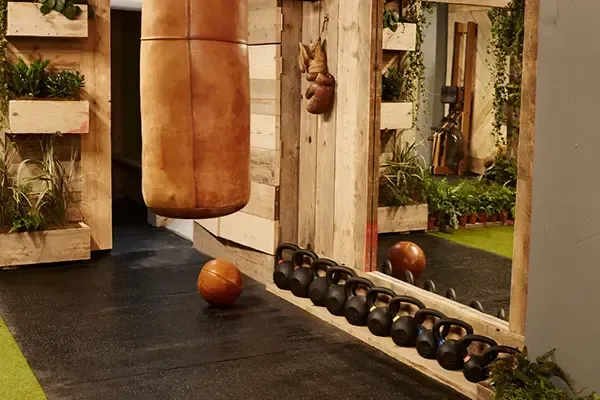 A boxing bag is hanging from the wall in a gym next to a mirror.