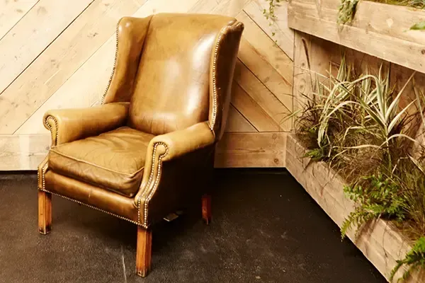 A brown leather chair is sitting in a room next to a wooden wall.