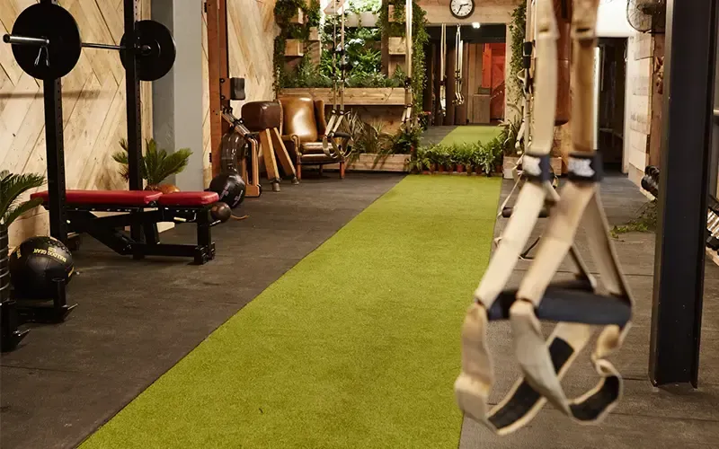 A trx strap is hanging from a barbell in a gym.