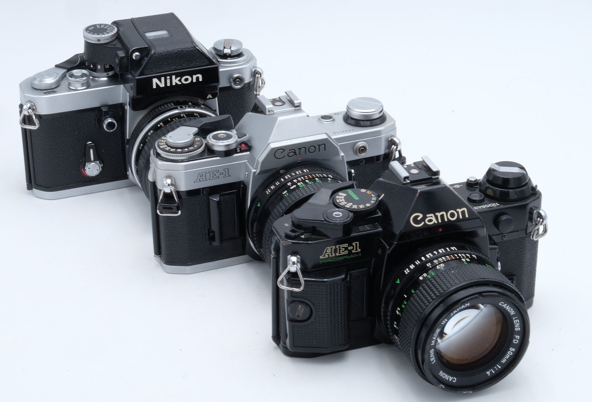 Trois appareils photos argentiques, deux Canon et un Nikon, datant des années 80.