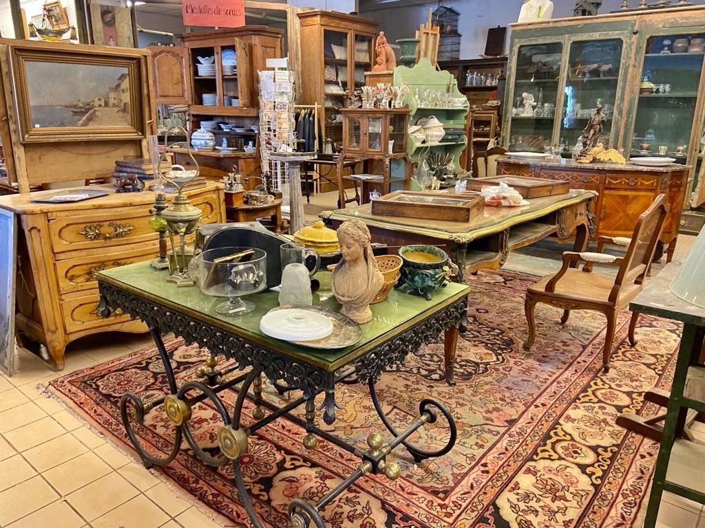 Espace chez un antiquaire présentant du mobilier en bois autour d'une table avec de la décoration et de la vaisselle