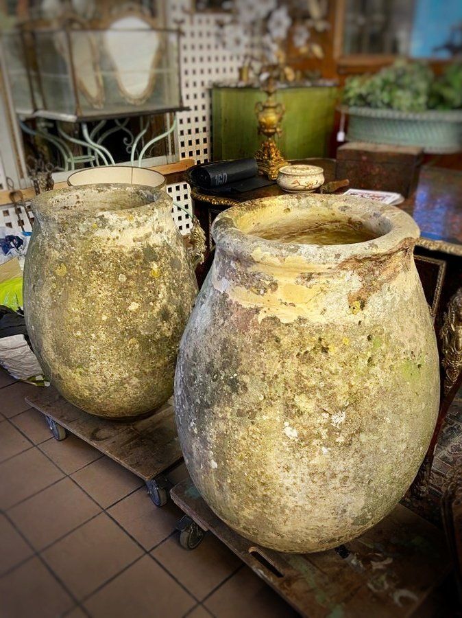 Vue large de deux grands pots en terre usés placés sur une planche à roulettes