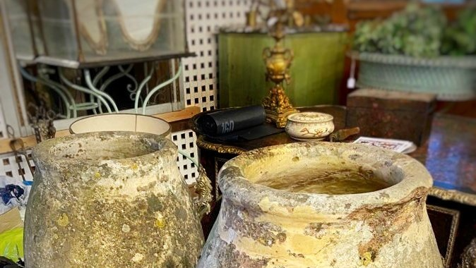 Deux grands pots en terre anciens au milieu d'autres produits chez un antiquaire