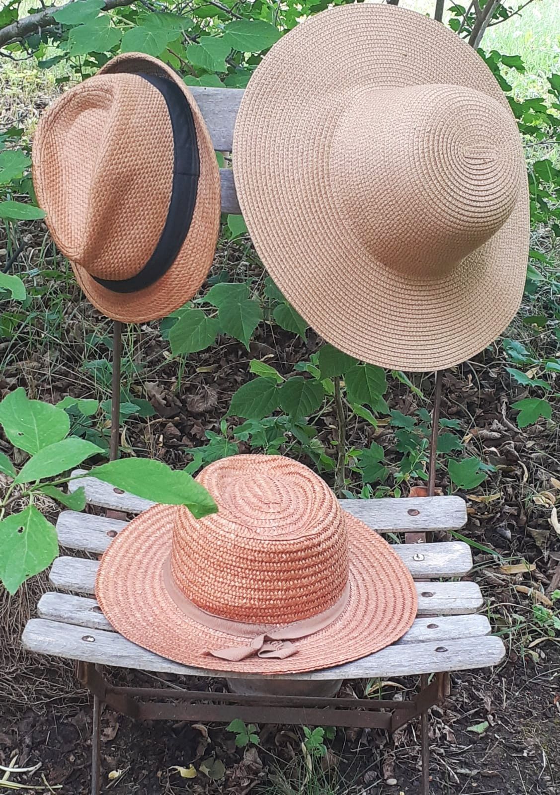 Trois chapeaux d'occasion en paille présentés sur une chaise en bois