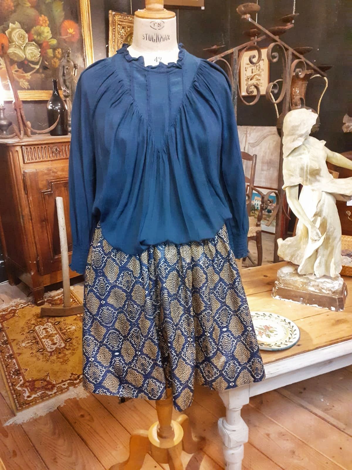 Ensemble de vêtements pour femme présenté chez un antiquaire sur un mannequin, avec jupe et haut