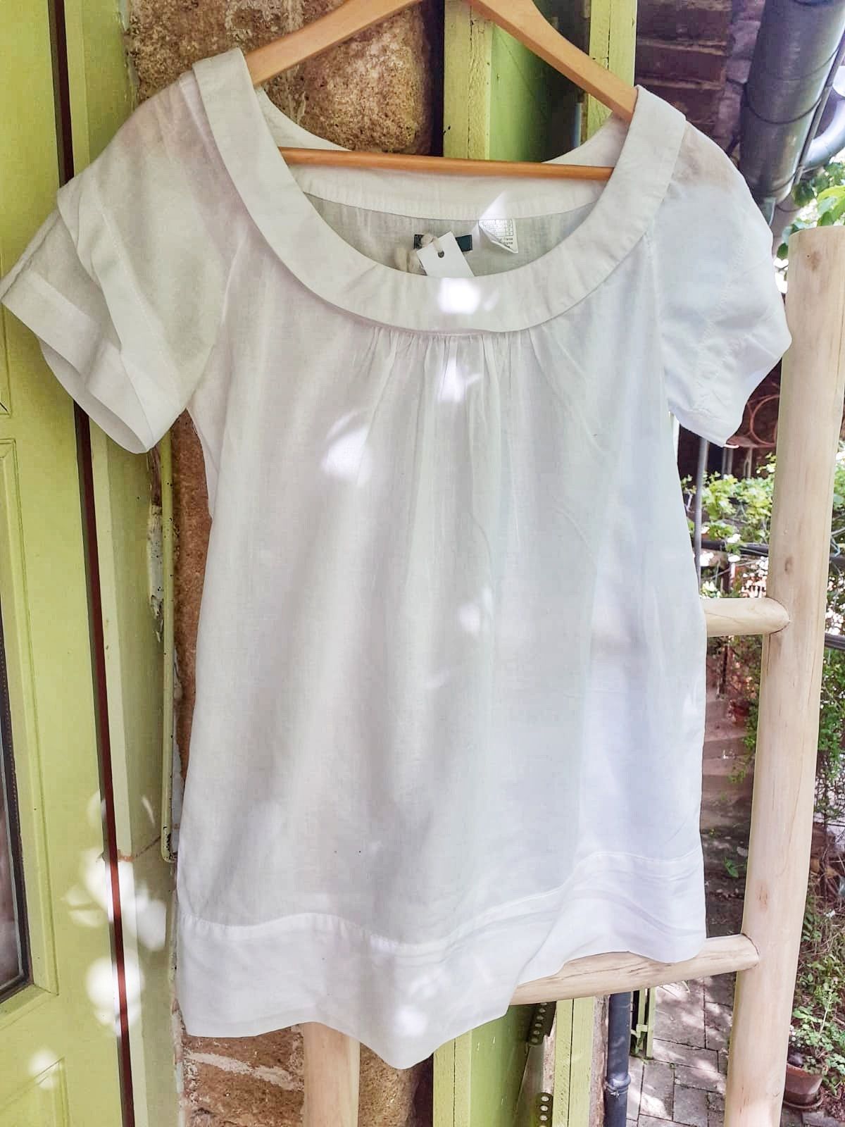 Haut blanc léger apparemment pour femme suspendu à un cintre dehors