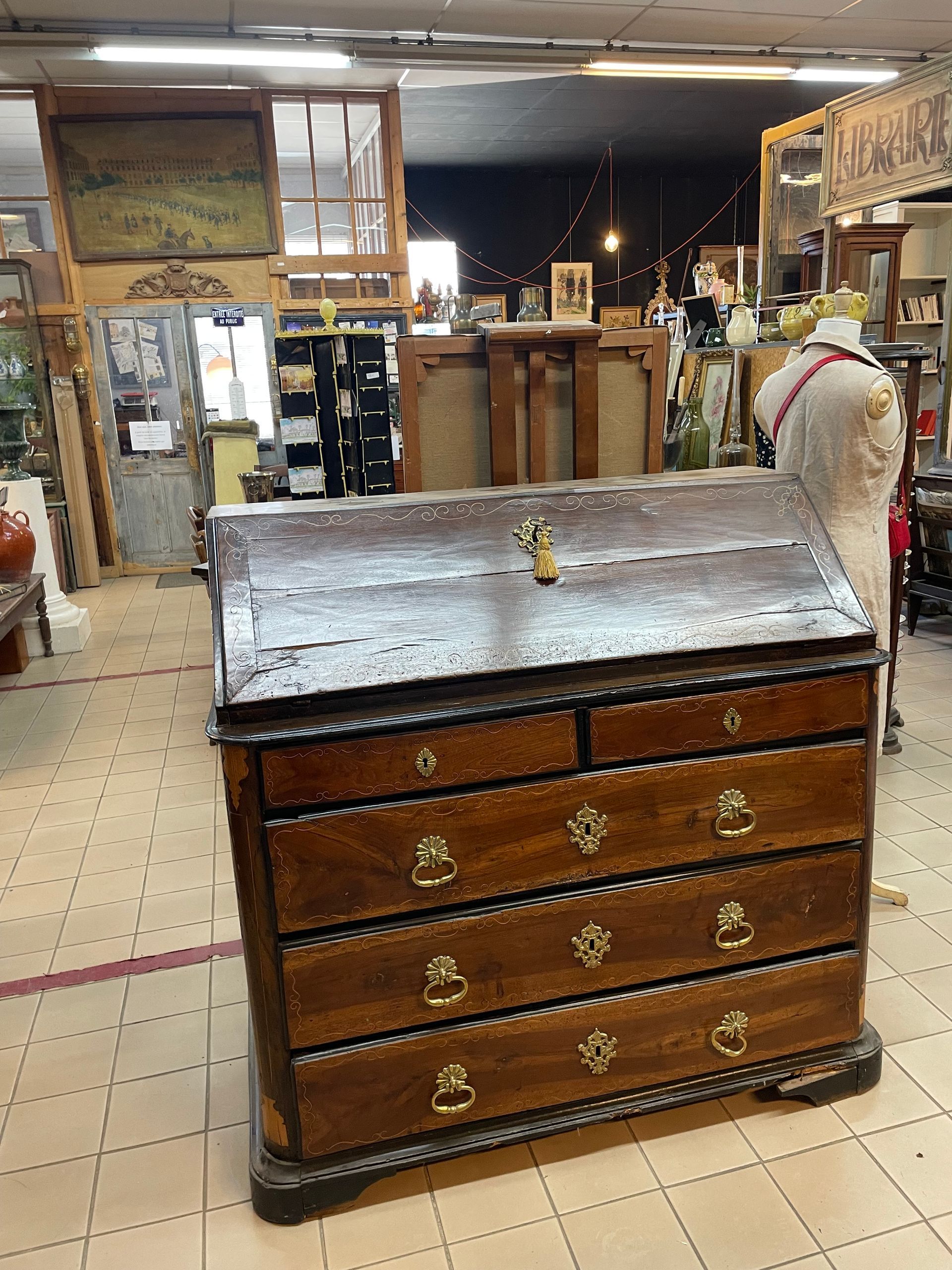 Meuble en bois chez un antiquaire avec plusieurs tiroirs et des dorures discrètes