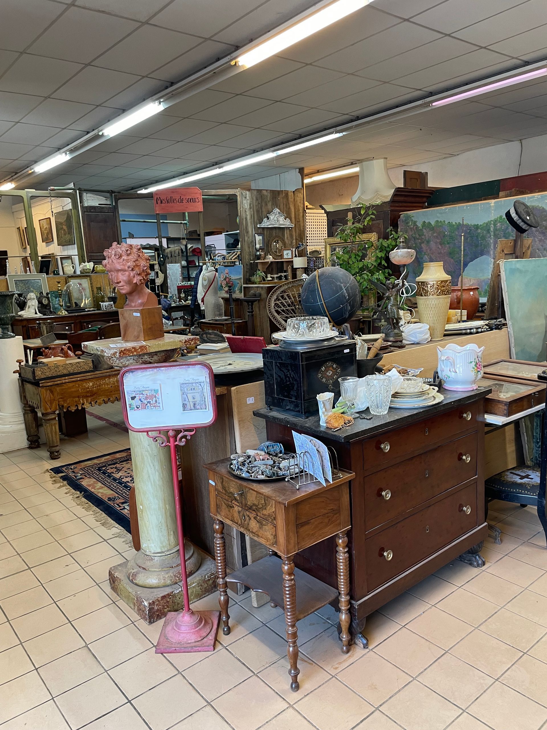 Pièce principale de la boutique d'un antiquaire avec des meubles en bois divers, de la vaisselle, des objets décoratifs