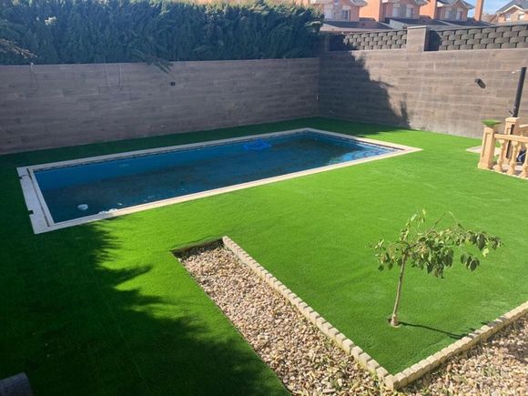 Una gran piscina está rodeada de un exuberante césped verde.