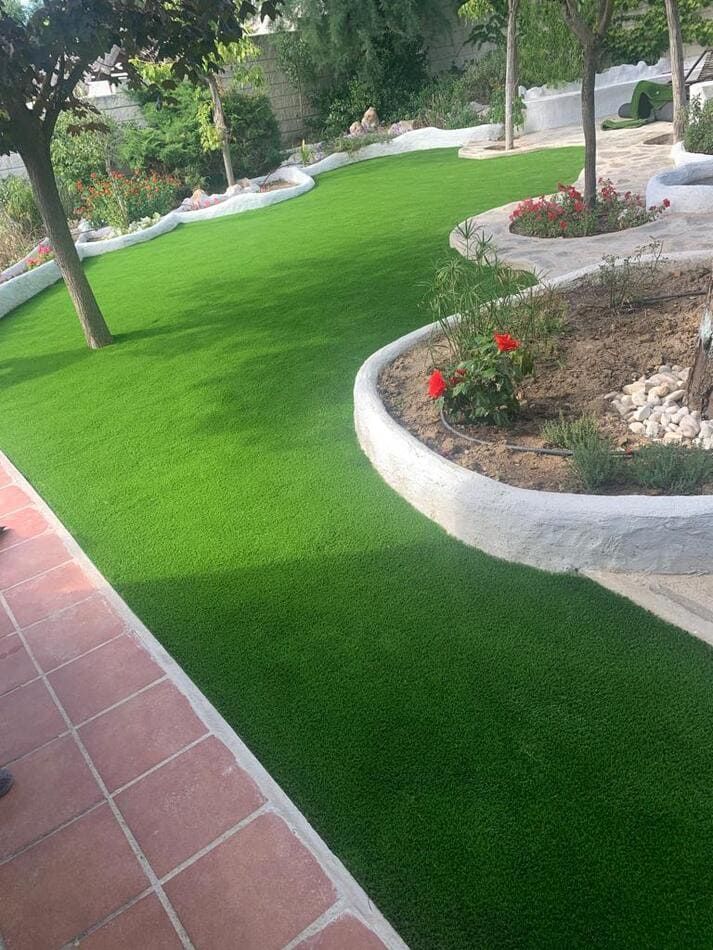 Un exuberante césped verde con flores y árboles en un jardín.