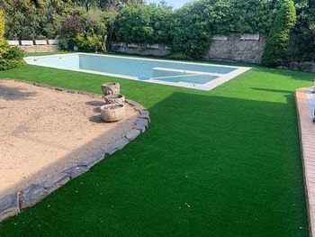 Una gran piscina está rodeada de un exuberante césped verde.