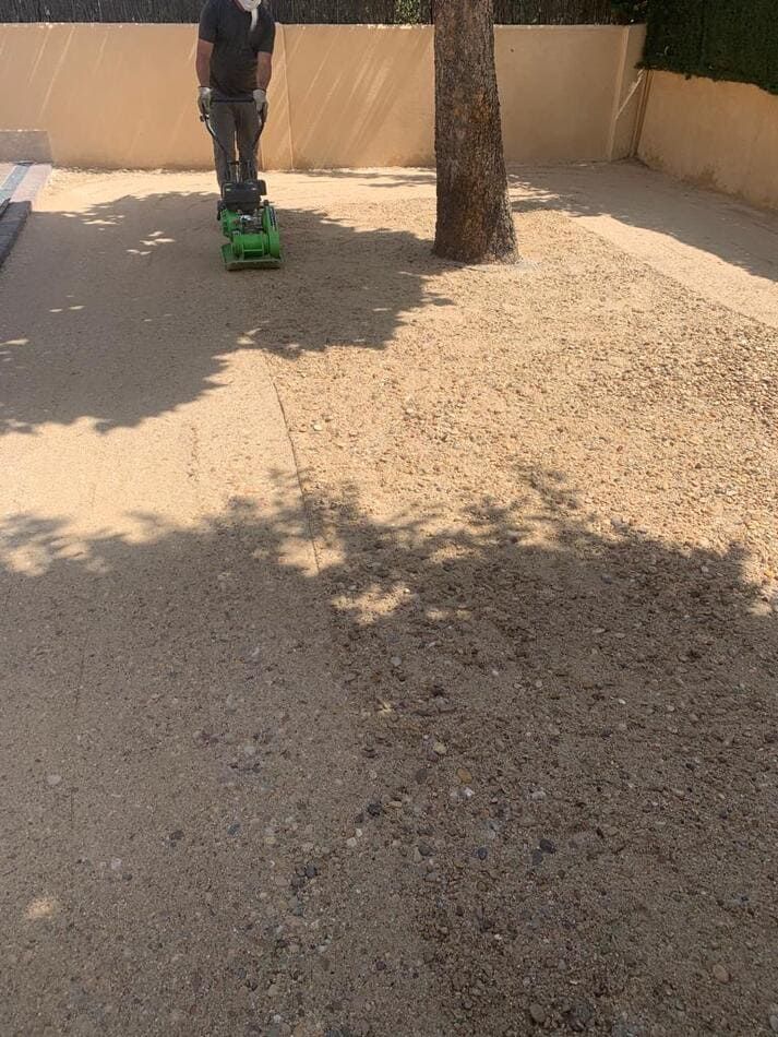 Un hombre viaja en un coche de juguete verde sobre una superficie de hormigón.