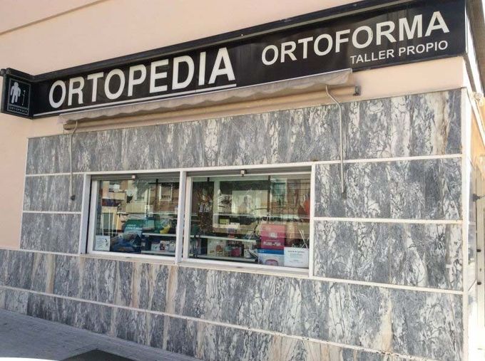 Fachada de una tienda de ortopedia con revestimiento de mármol y un gran letrero que dice 