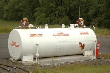 Cuve de stockage de carburant blanche sur un terrain gravillonné.