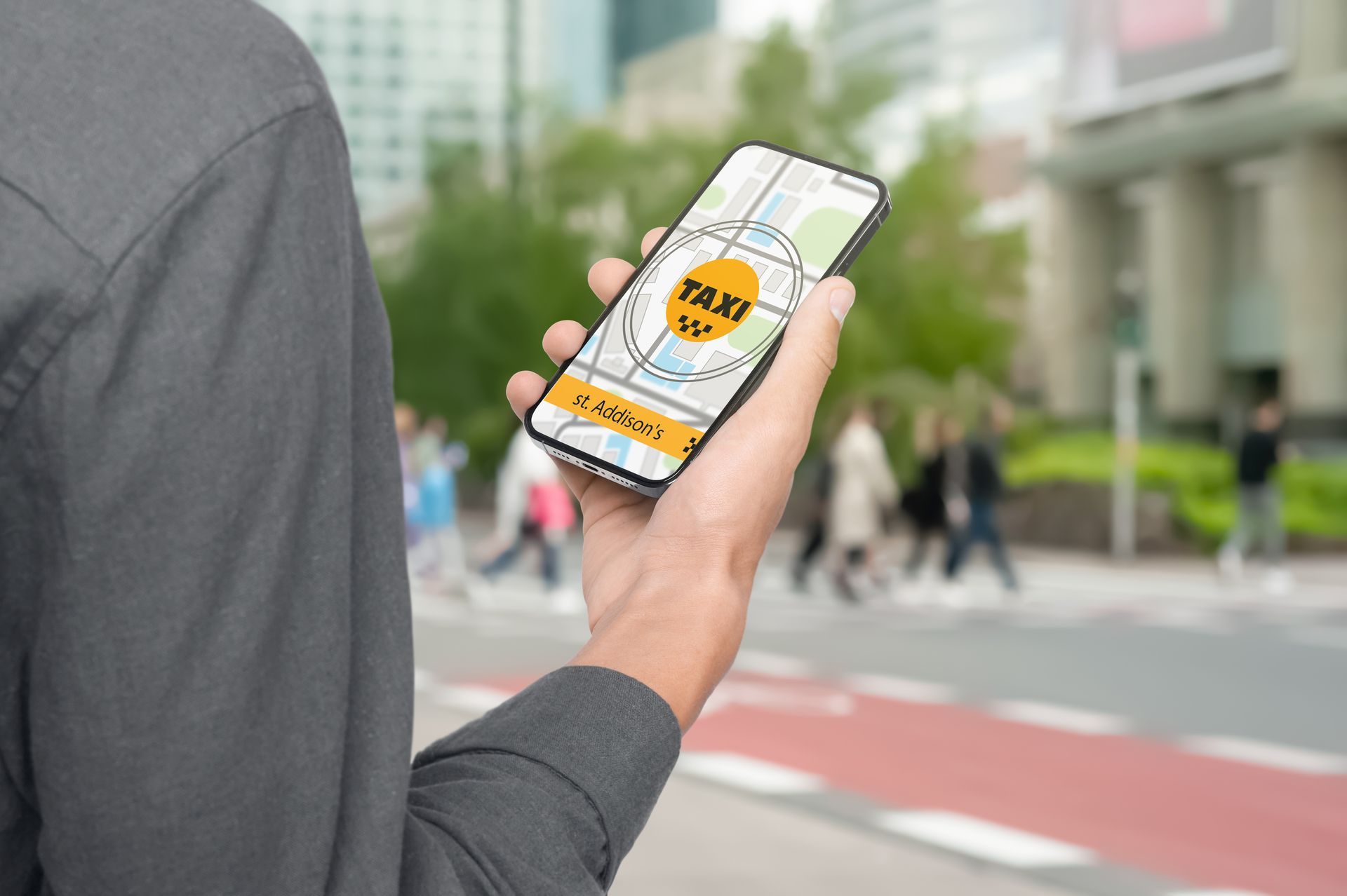 Une personne tenant un smartphone affichant une application de taxi avec une rue en arrière-plan.