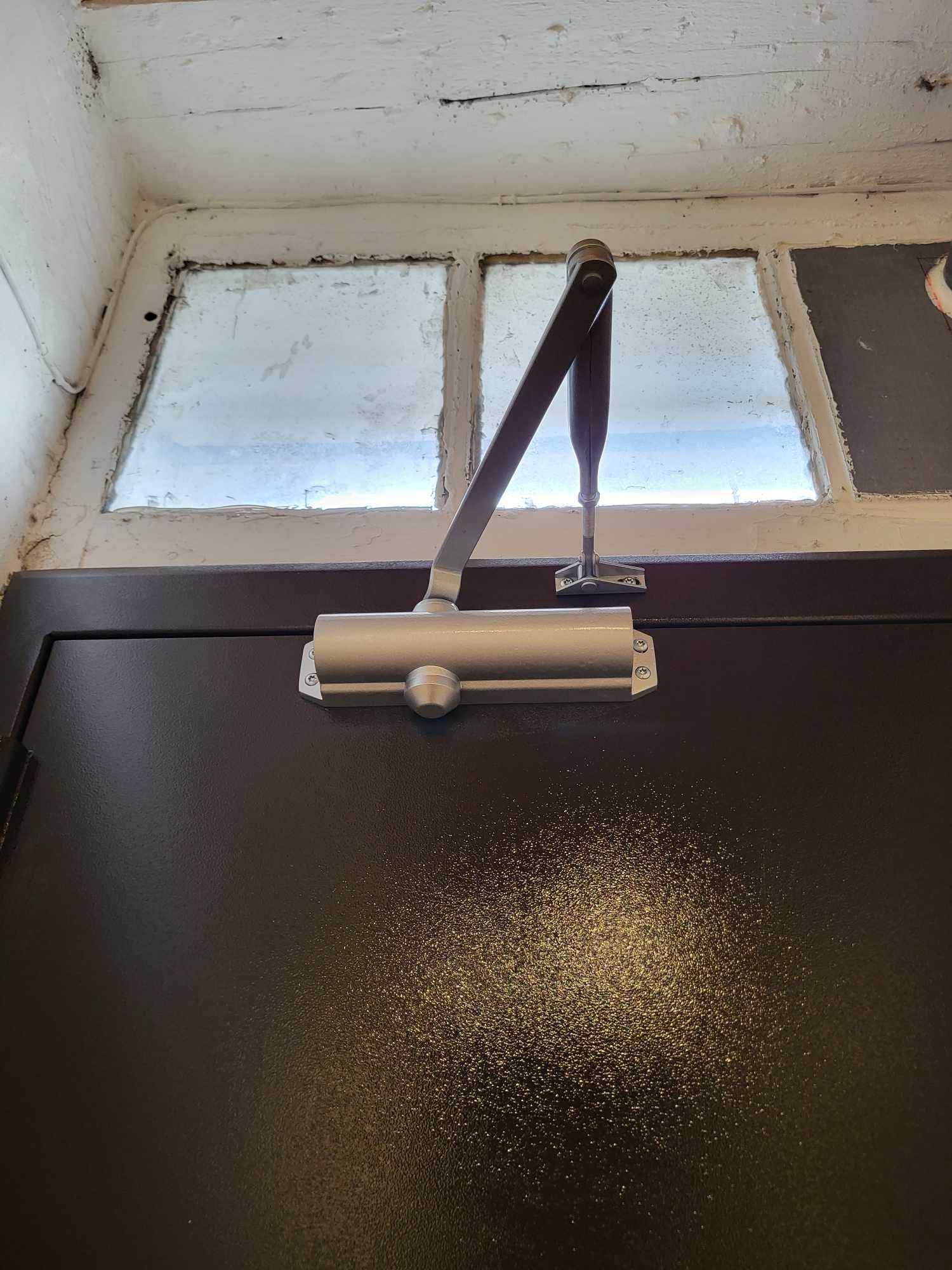 Porte d'immeuble équipée d'un ferme-porte