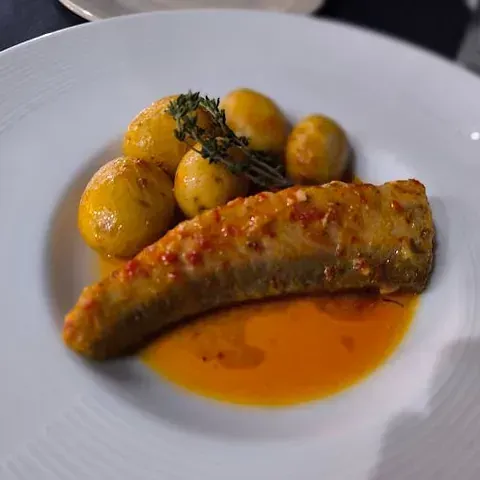 Un plato blanco cubierto con un trozo de carne y patatas.