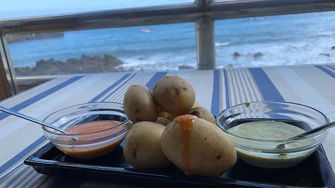 Un plato de comida con salsas en una mesa con vista al océano.