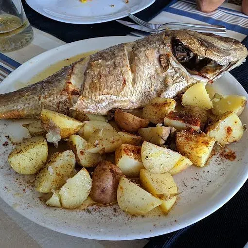 Un plato de comida con pescado y patatas en una mesa.