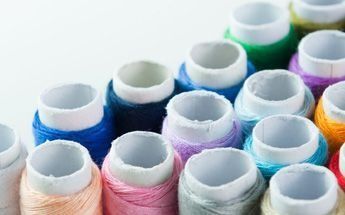 Carretes de hilo de colores en distintos tonos, dispuestos muy juntos.