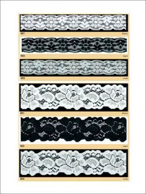 Muestras de adornos de encaje en blanco y negro, con diseños florales y estampados, expuestos sobre un fondo negro.
