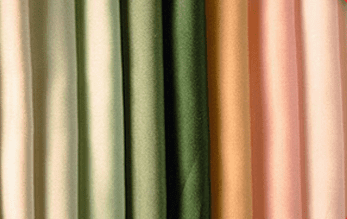 Primer plano de cuatro cortinas verticales en tonos beige claro, verde, tostado y rosa.