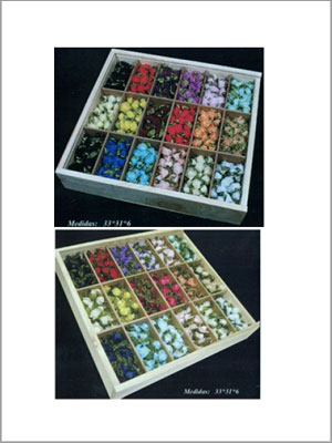 Dos cajas de madera divididas en compartimentos llenos de pequeñas flores artificiales de colores.