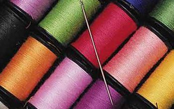 Carretes de hilo de colores con aguja. Concéntrese en la variedad de colores y la herramienta de costura.