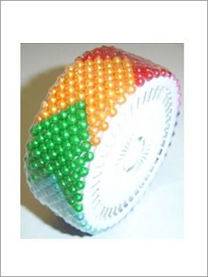 Porta-pins circular con alfileres de perla arcoíris. Centro blanco y fondo negro.