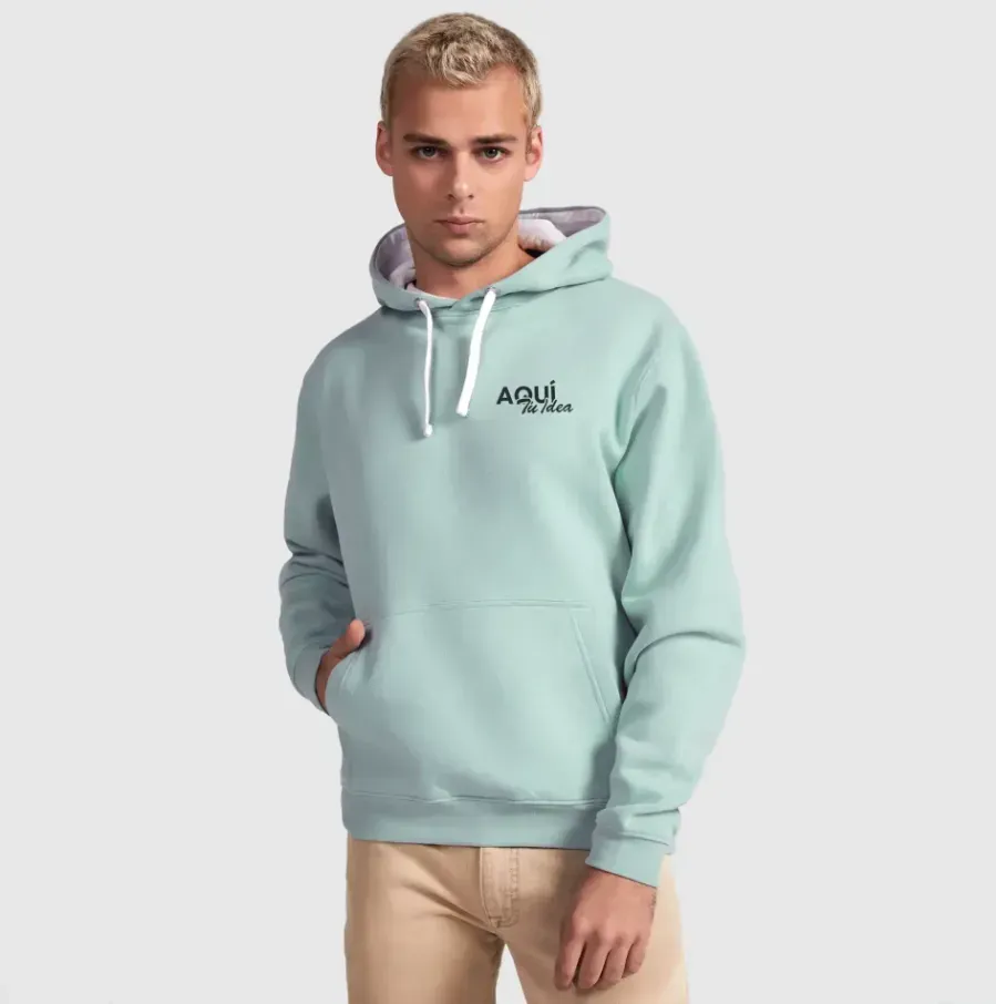 Hombre que lleva una sudadera con capucha verde claro con un pequeño logotipo, con las manos en el bolsillo delantero