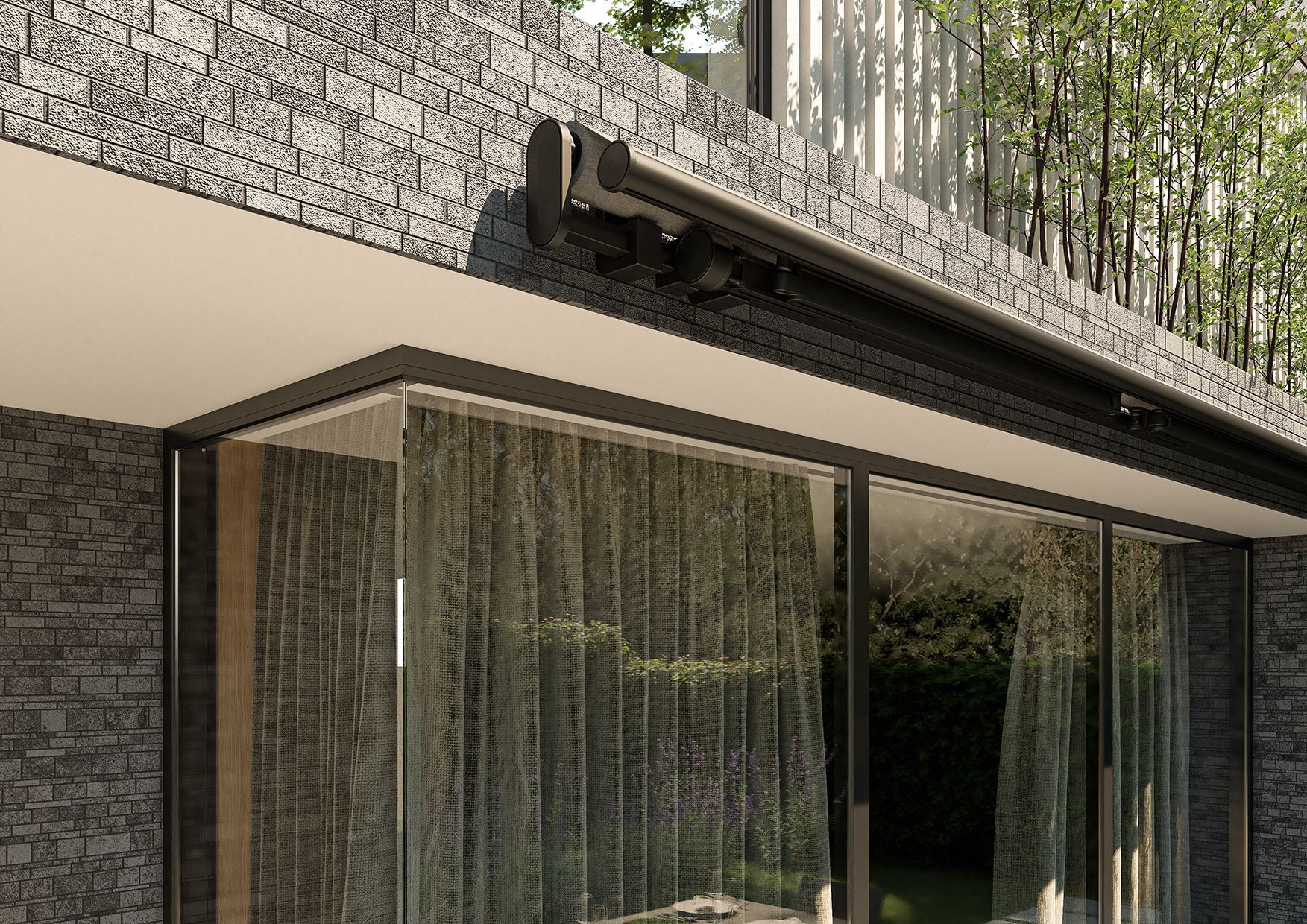 Una tenda da sole scura e retrattile, montata su un muro di pietra grigia sopra una porta scorrevole in vetro con tende trasparenti all'interno.