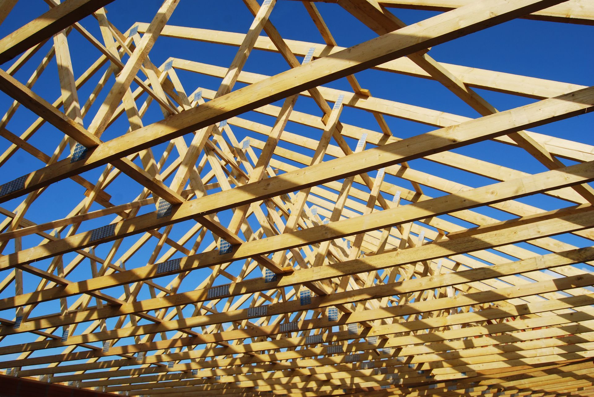 Fermes de toit en bois contre un ciel bleu vif.